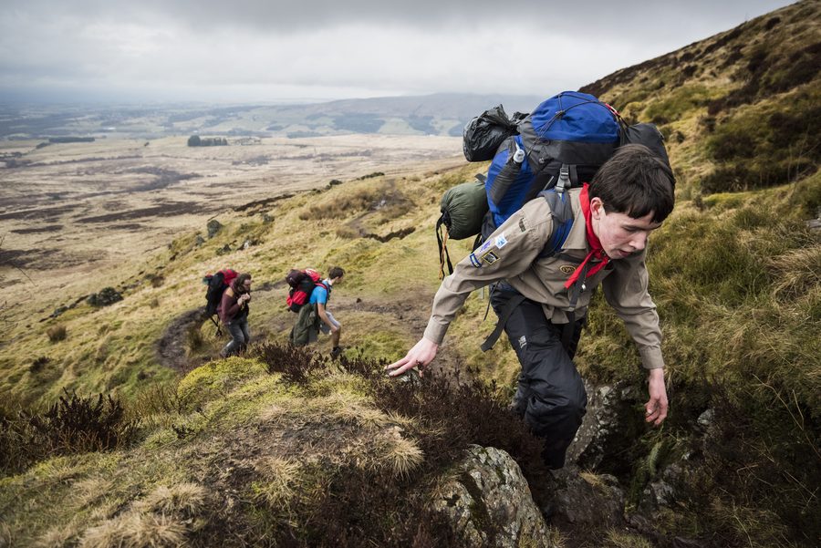 Young people with backpacks hiking across open moorland on an expedition
