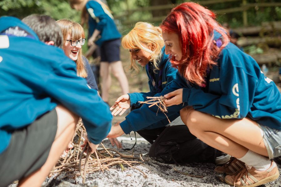Explorer Scouts building a campfire together in the woods