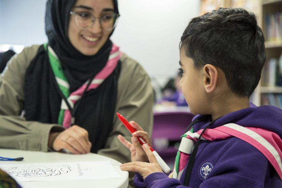 A volunteer leader helping a young child with a craft activity at a table