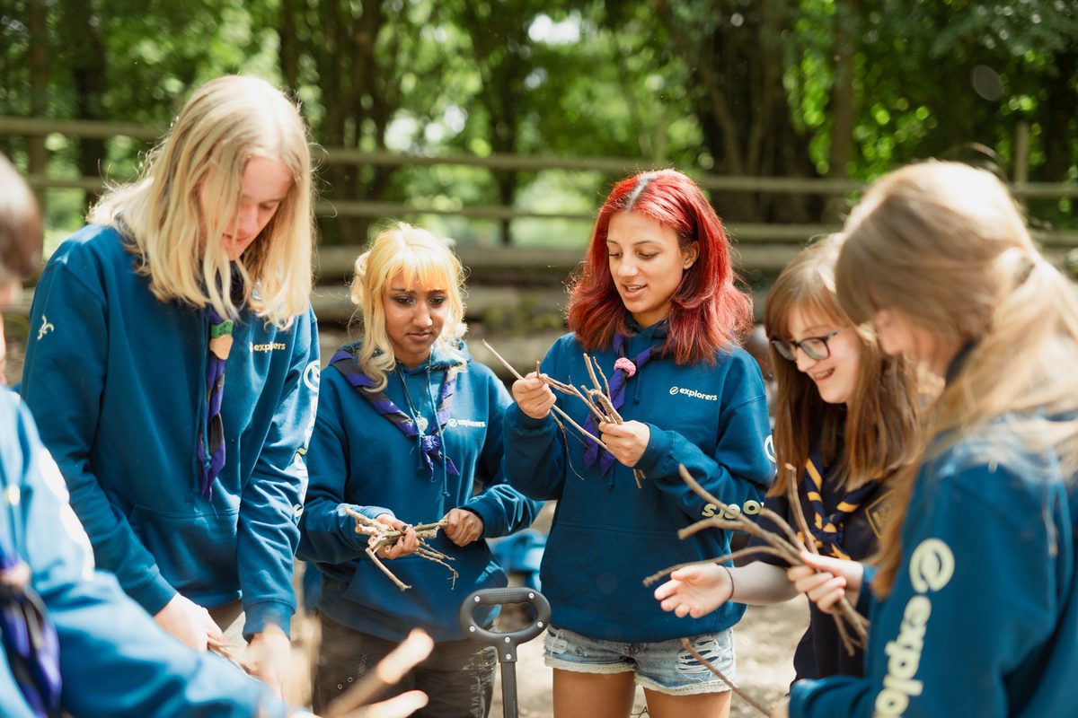 A group of Explorer Scouts gathering kindling together outdoors
