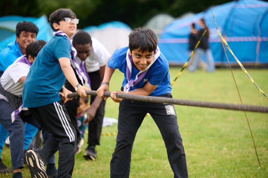 A team of Scouts pulling together in a tug of war outdoors