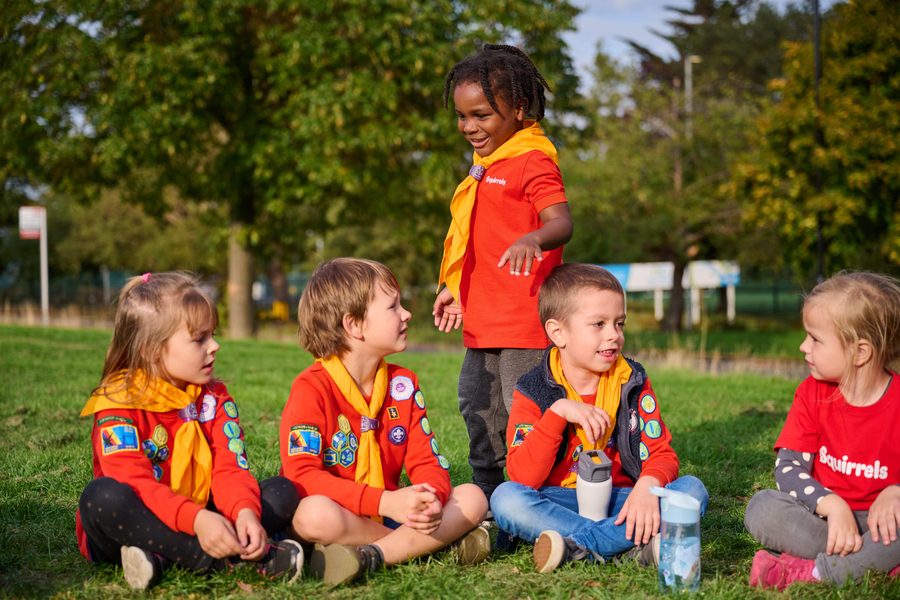 A group of Squirrels in red uniform sitting together on the grass, chatting