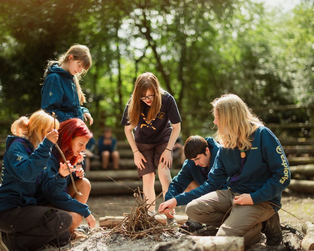 A line of young people with large backpacks hiking across open moorland on an expedition