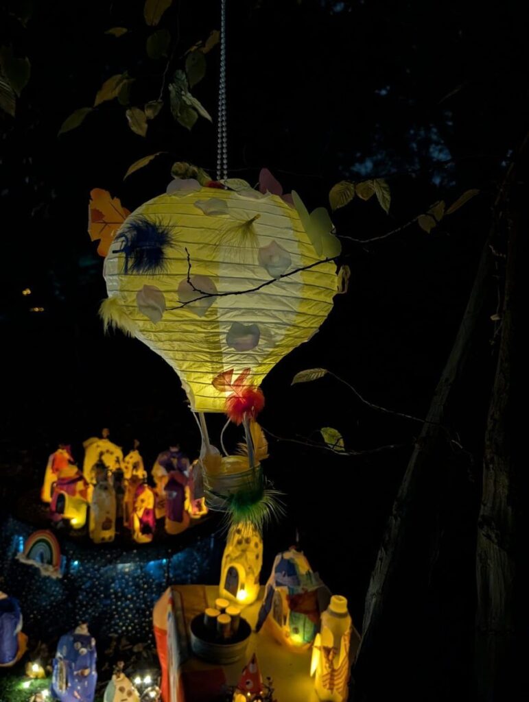 A glowing hot air balloon lantern hanging among the trees at the Glow Walk