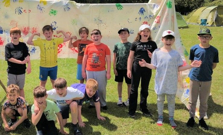 Harlington Scouts cheering in front of a hand-painted banner at camp