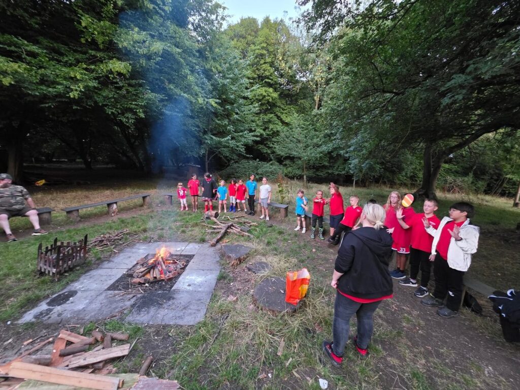 St Anne's Scouts gathered around a campfire in the woods