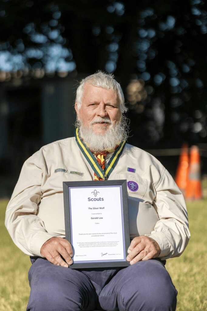 Gerald Law seated with his framed Silver Wolf certificate